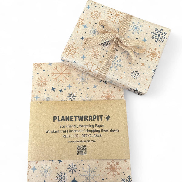 PlanetWrapIt recycled kraft wrapping paper in Christmas Snowflakes (brown paper with printed colourful snowflakes shown alongside wrapped parcel with gold ribbon