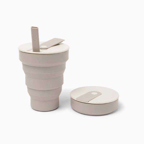 Collapsible cup 16oz shown in warm grey up with flexible straw alongside collapsed