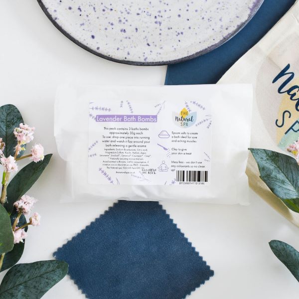 The Natural Spa Bath bombs in shown in paper packaging in lavender scent (purple font)