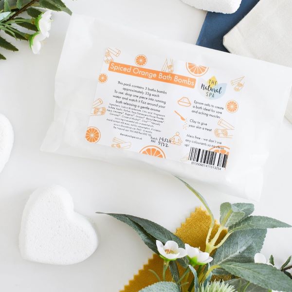 The Natural Spa Bath bombs in shown in paper packaging in spiced orange scent (orange font)
