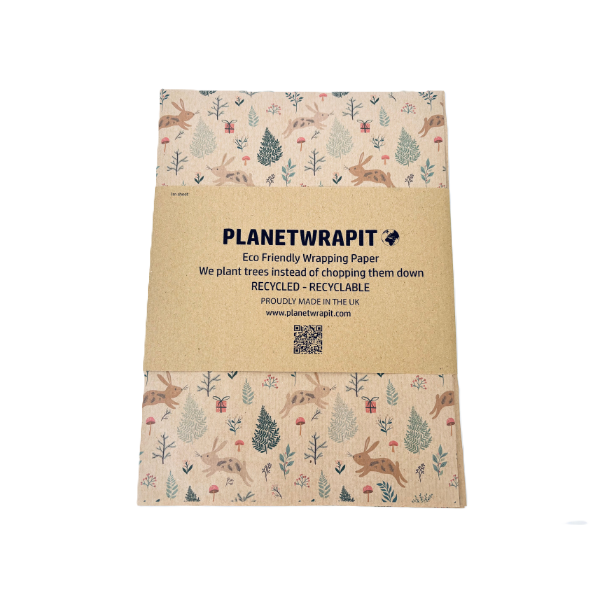 Handmade recycled Christmas paper in Christmas bunnies design, kraft paper background with colourful leaping bunnies and woodland scenes, shown with paper band label