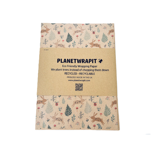 Handmade recycled Christmas paper in Christmas bunnies design, kraft paper background with colourful leaping bunnies and woodland scenes, shown with paper band label