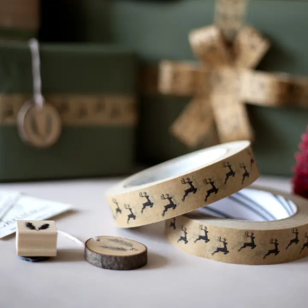 Christmas paper tape brown with black reindeers shown on rolls next to wrapped parcels and Christmas stamps