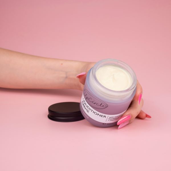 UpCircle conditioner creme held in a person's hand with lid off