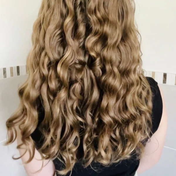 Person with long, soft, curly hair shown from behind