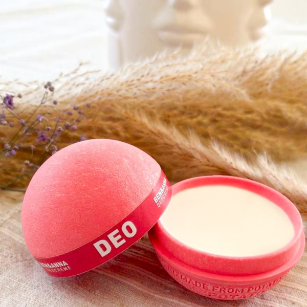 Natural deodorant cream in potato based packaging, a pink sphere with lid off showing deodorant inside
