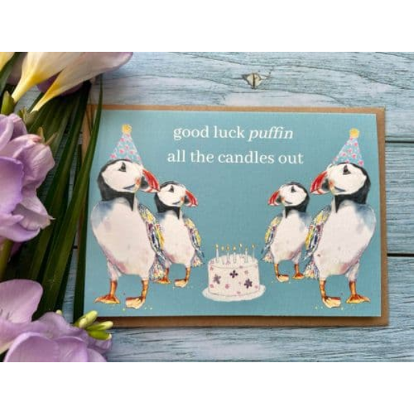 Eco birthday card, blue background with 4 puffins with party hats and a birthday cake with the words "good luck puffin all the candles out"