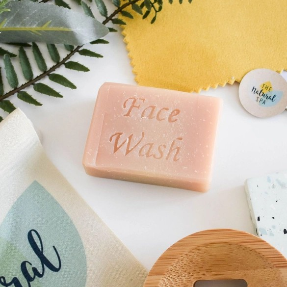 Travel facial soap bar (grapefruit and lemongrass) shown with greenery and a wooden soapdish, the words 'Facial wash' stamped on the bar