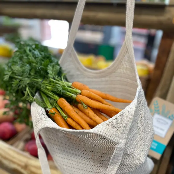 Lace bag in natural pale cream colour shown with carrots including their green stalks inside