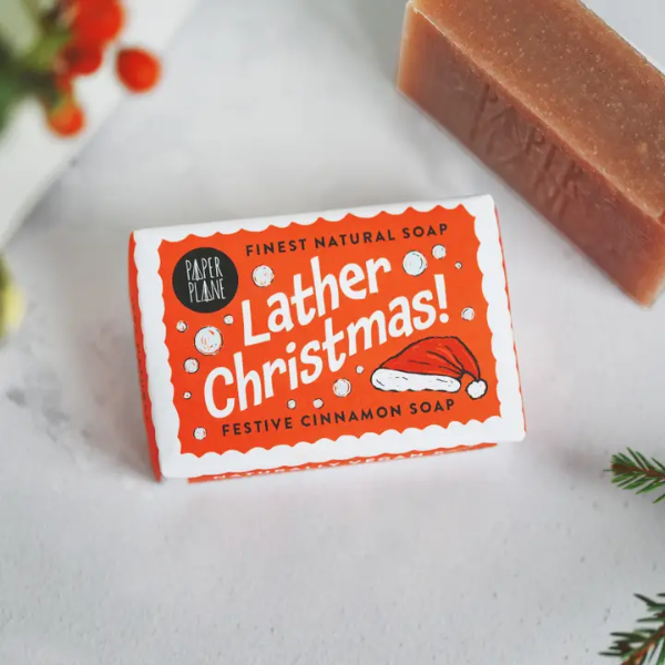Lather Christmas soap bar shown unwrapped and wrapped in paper with festive decoration