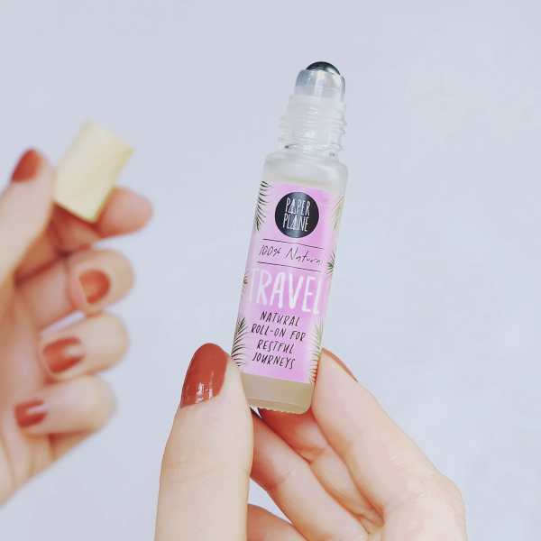 Natural pulse point roll on in hand showing bamboo lid in one hand, with text on label reading '100% natural Travel natural roll-on for restful journeys'