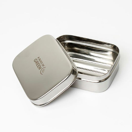 Travel soap or snack tin with lid shown off to see ridged base inside. Lid has logo reading A Slice of Green.