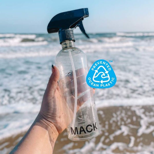 Mack reusable spray bottle held in a hand on a beach with logo saying Prevented Ocean Plastic