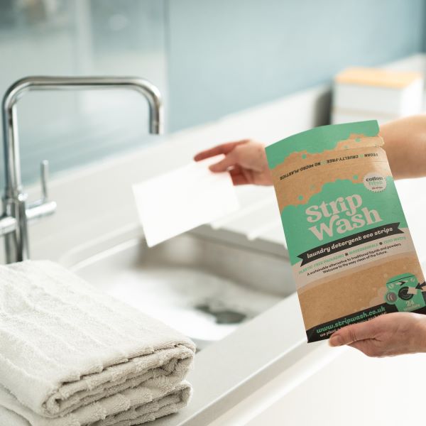 Laundry detergent strip being popped in hot water for hand washing