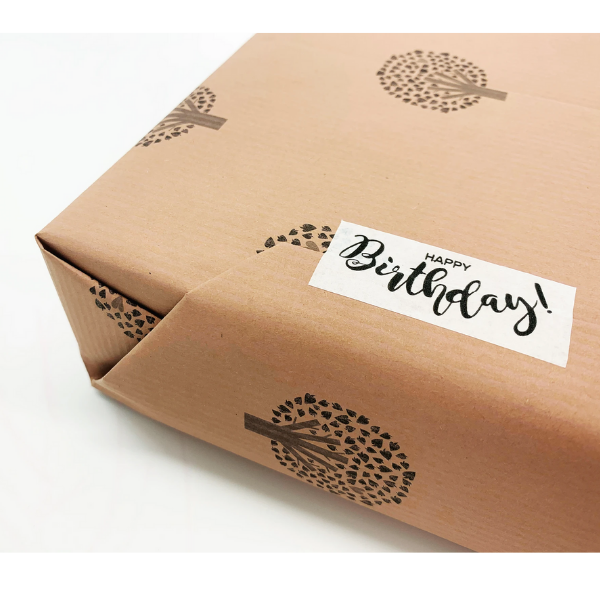 Eco-friendly paper tape (white) with "Happy Birthday!" written in black font attached to a brown paper parcel