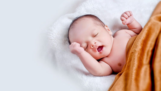 Baby yawning and lying on white cotton with a rust coloured blanket
