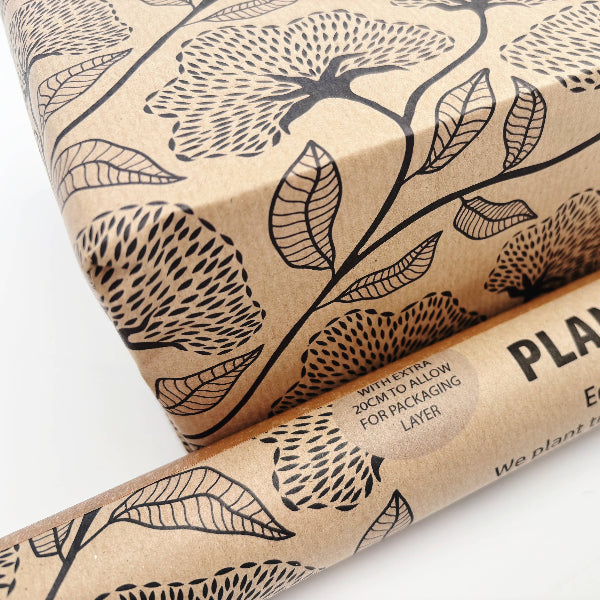 Planet Wrapit eco-friendly kraft wrapping paper with black floral design and PlanetWrapIt paper label shown close up alongside wrapped parcel.