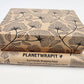 Planet Wrapit eco-friendly kraft wrapping paper with black floral design and PlanetWrapIt paper label shown alongside wrapped parcel.