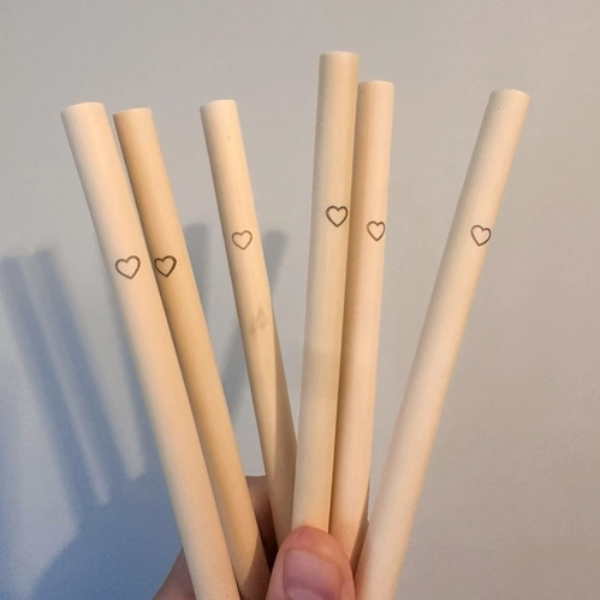 Several bamboo heart straws held in a hand 
