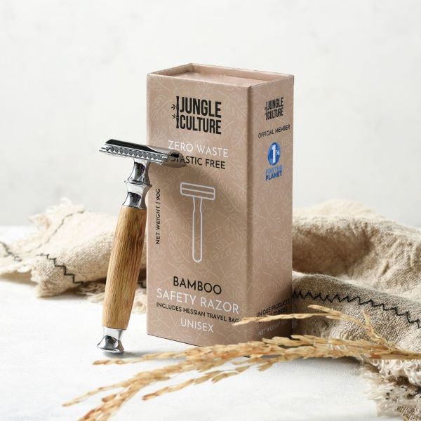 Bamboo safety razor with light wood thick handle shown balanced against cardboard packaging