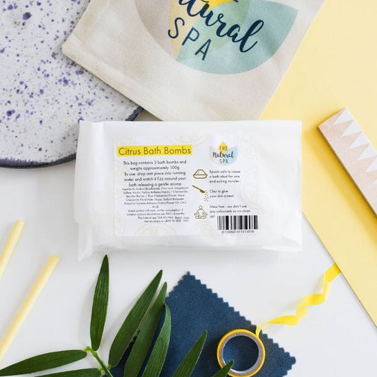 The Natural Spa Bath bombs in shown in paper packaging in citrus scent (yellow font)