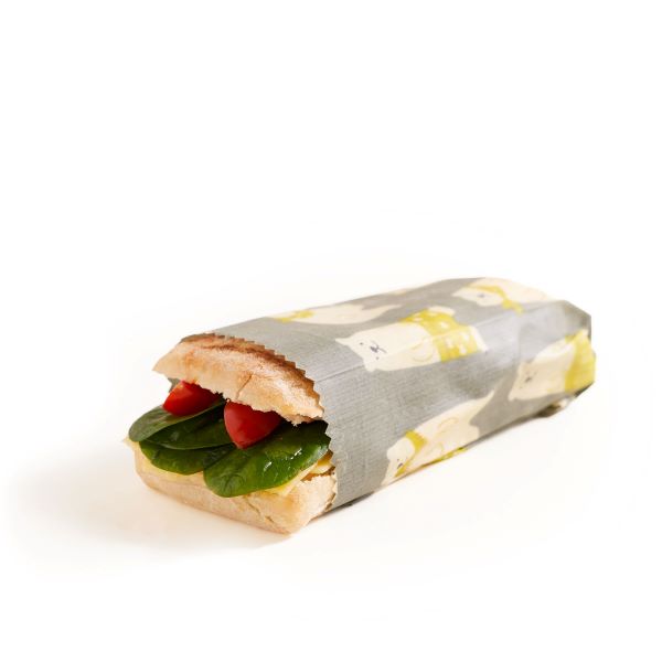 Beeswax wrap in animal print (grey background with polar bears in yellow shorts) wrapped around a large sandwich