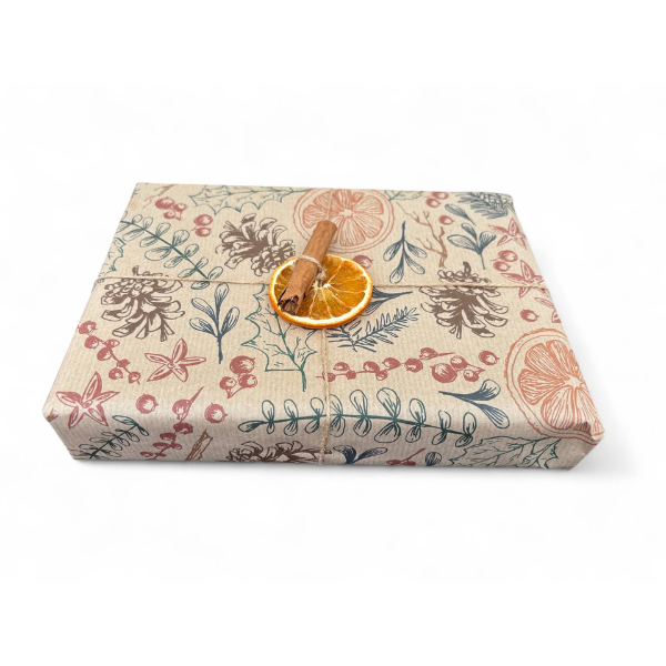 PlanetWrapI recycled kraft wrapping paper in Christmas dried orange (brown background with images of dried oranges, pine cones, foliage) shown on a wrapped parcel with dried orange and cinnamon
