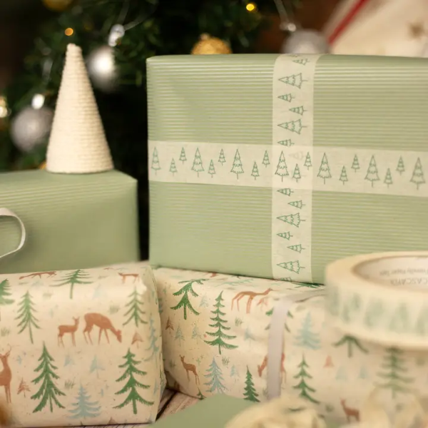 Christmas paper tape white with green Christmas trees shown on a parcel wrapped in green paper with the tape making a decorative cross