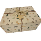 Handmade recycled Christmas wrapping paper in Woodland friends (brown kraft paper with hand-drawn style woodland creatures and Christmas trees) on a wrapped gift with twine and a natural jute bow and paper star tag