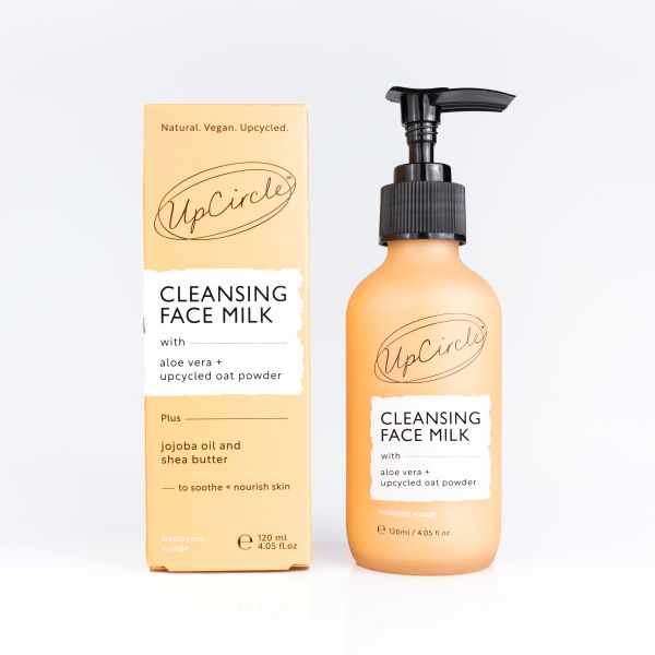 Cleansing face milk in glass bottle with black pump alongside cardboard box packaging