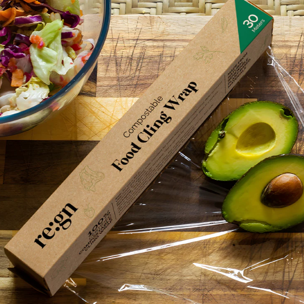 Compostable cling film shown in cardboard dispenser alongside sliced avocado