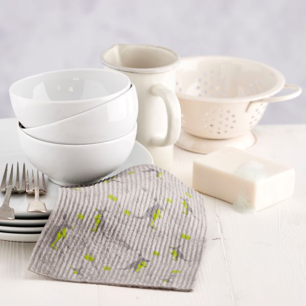 Compostable sponge cloth in grey with kangaroos, next to some dishes