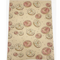 Eco-friendly recyclable wrapping paper in doughnuts design (brown paper with pink and white sprinkled doughnuts) shown close up