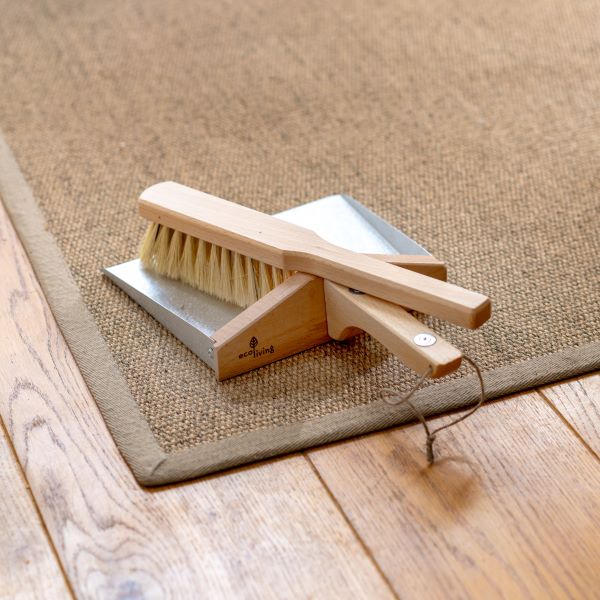 Plastic-free dustpan and brush set with steel pan, wooden brush with natural bristles lying on a rug