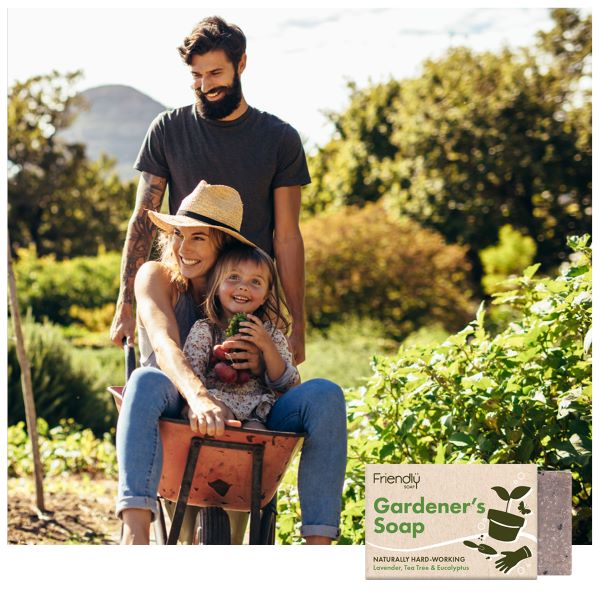 A man pushing a wheelbarrow with a laughing woman and child in a lush green garden, with the gardener's soap bar image inset