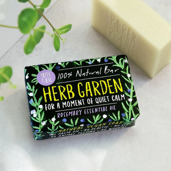 Herb garden rosemary soap bar shown wrapped (with text reading "for a moment of quiet calm") alongside an unwrapped bar
