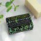 Herb garden rosemary soap bar shown wrapped (back view with text reading "with fragrant rosemary oil to evoke the tranquillity of a herb garden") alongside an unwrapped bar