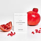 Perfume balm in white cardboard packaging with packaging reading "Optimistic/Adventurous/Playful Italian Summer solid perfume" shown alongside pomegranates and seeds