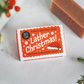 Lather Christmas soap bar shown unwrapped and wrapped in paper with festive decoration 