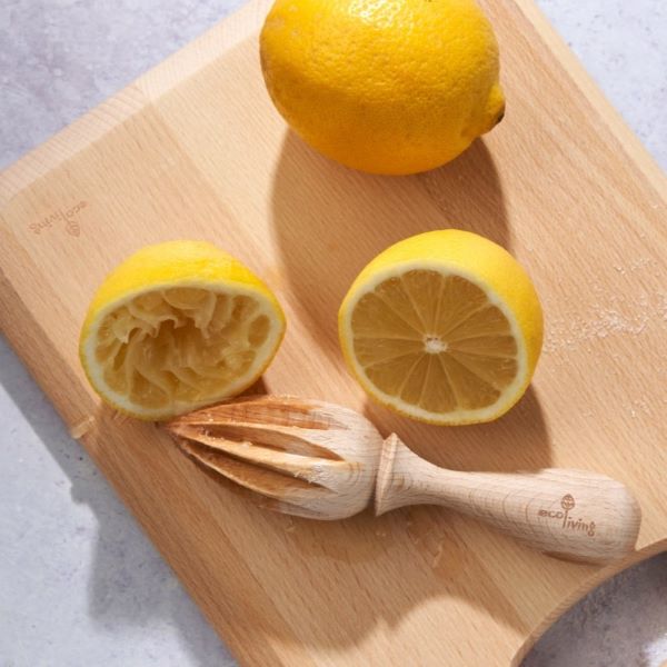 Wooden lemon reamer shown on a wooden chopping board with a lemon cut in half