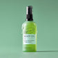Green bottle of UpCircle body oil on a green background with drips of oil coming down the bottle