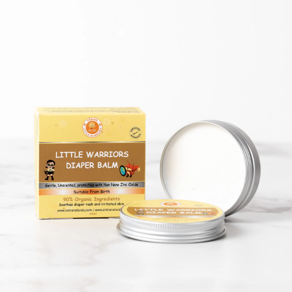 Little Warriors diaper balm in aluminium tin shown with lid off and balm inside, next to cardboard box packaging