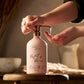 Refillable aluminium bottle in blush pink with a hand  pressing the pump with product coming out