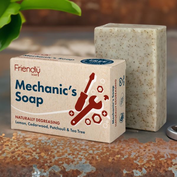 Friendly Soap mechanic's soap bar shown alongside its cardboard packaging on a rusty metal surface