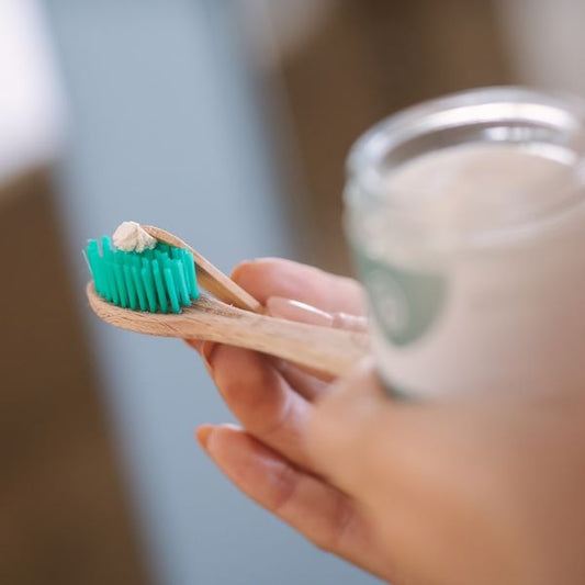 Georganics mineral toothpaste scooped out and being applied onto a bamboo toothbrush