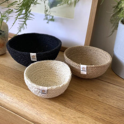 Set of three mini jute bowls in Fire colour (bright pink, orange and yellow)  sitting on a wooden table top