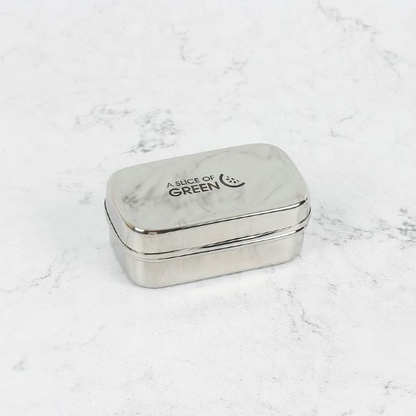 Mini stainless steel mini snack container shown on a marble surface with lid on, with A Slice of Green logo