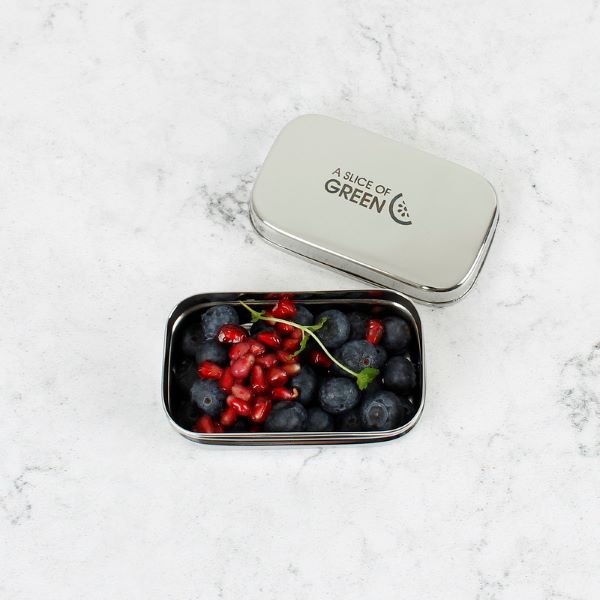 Mini stainless steel snack container shown on a marble surface with lid off showing contents inside (blueberries and pomegranate seeds)