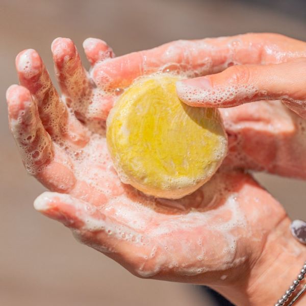 Cleansing shampoo bar in hand with lather