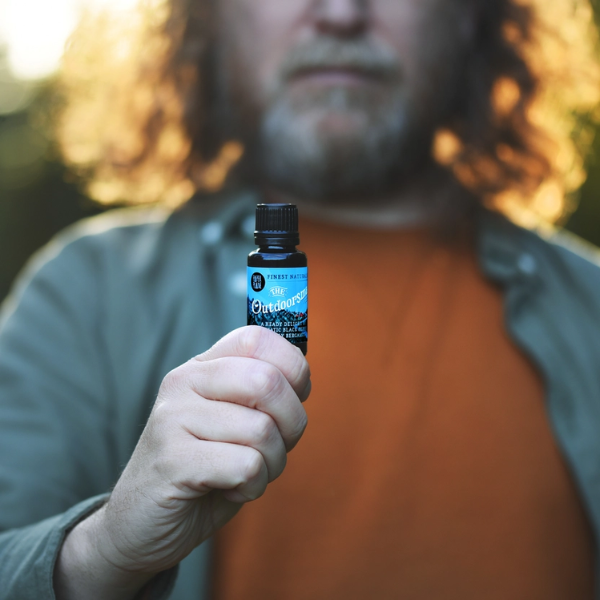 The Outdoorsman bear oil in glass bottle sitting in a person's hand